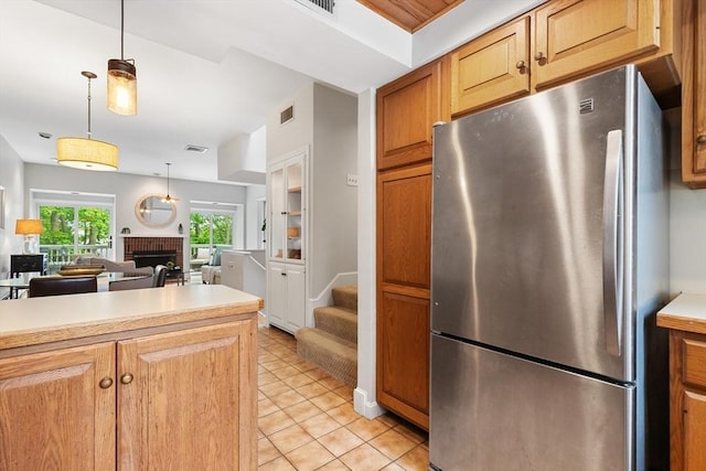 64 Prospect St Unit B, Marblehead, MA 01945 - kitchen with freestanding refrigerator, light countertops, a brick fireplace, light tile patterned flooring, and decorative light fixtures