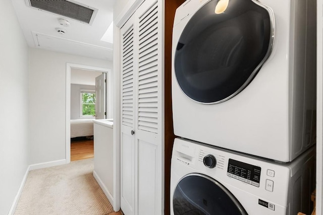 64 Prospect St Unit B, Marblehead, MA 01945 - washroom featuring stacked washer and clothes dryer, baseboards, light colored carpet, and attic access