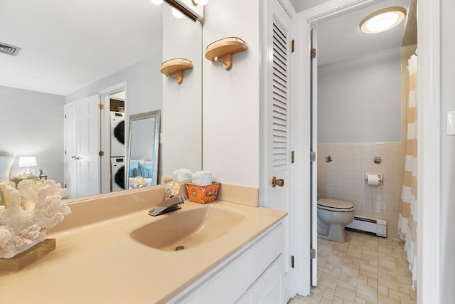 64 Prospect St Unit B, Marblehead, MA 01945 - bathroom with stacked washer and clothes dryer, a baseboard heating unit, a closet, toilet, and tile walls