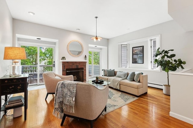 64 Prospect St Unit B, Marblehead, MA 01945 - living area featuring baseboard heating, wood finished floors, a brick fireplace, and baseboards