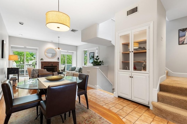 64 Prospect St Unit B, Marblehead, MA 01945 - dining space with a brick fireplace, stairs, light tile patterned floors, and baseboards