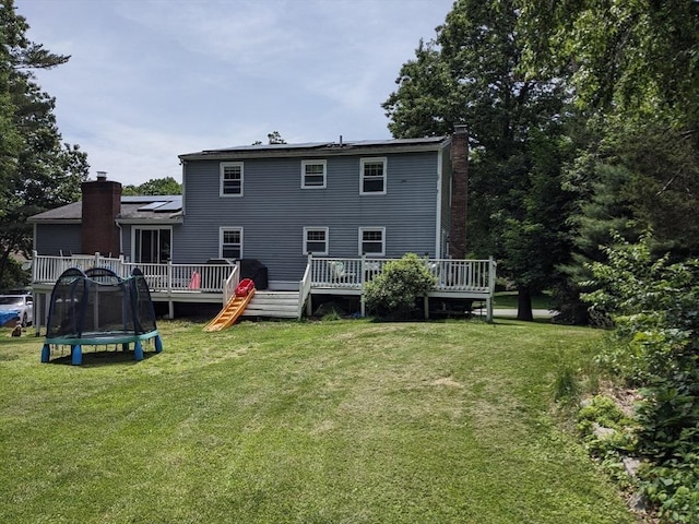 38 Pearson Dr, Newbury, MA 01922 - back of house with a chimney, a yard, a deck, and a trampoline