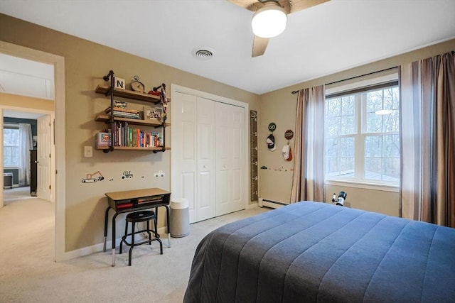 carpeted bedroom featuring ceiling fan, a closet, and a baseboard heating unit