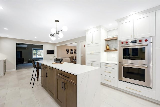 kitchen with hanging light fixtures, white cabinetry, a kitchen island, and stainless steel double oven