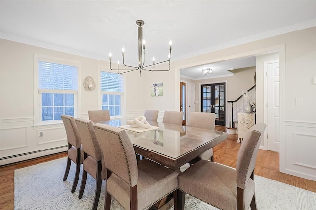 dining area featuring french doors, an inviting chandelier, light hardwood / wood-style flooring, a baseboard radiator, and ornamental molding