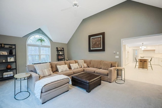 carpeted living room with ceiling fan with notable chandelier and high vaulted ceiling