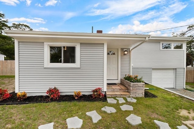 view of front of house featuring a garage, a front lawn, and fence