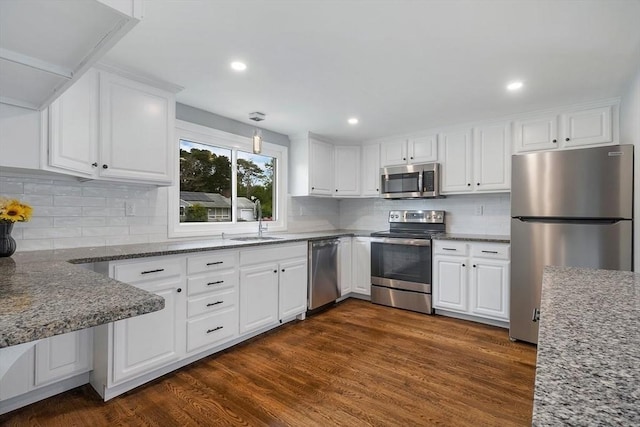 kitchen with a sink, stainless steel appliances, dark wood finished floors, and white cabinetry