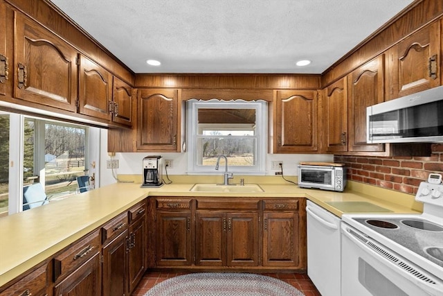 kitchen with white appliances, kitchen peninsula, sink, and a textured ceiling