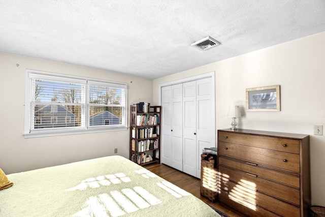 bedroom with dark hardwood / wood-style floors, a closet, and a textured ceiling