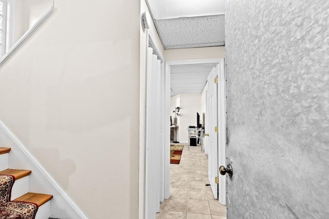 hallway with light tile patterned flooring and a paneled ceiling