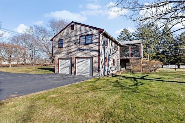 view of side of property featuring a garage, a sunroom, and a lawn