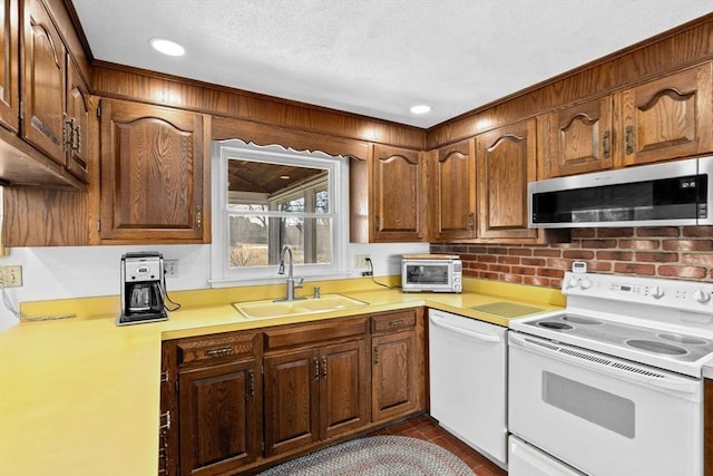 kitchen featuring sink, white appliances, and a textured ceiling