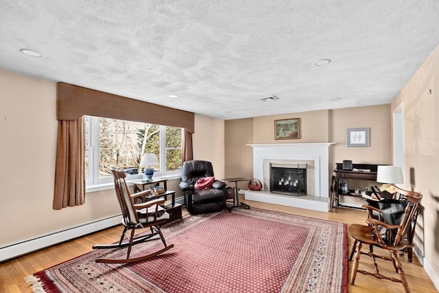 living area featuring wood-type flooring, a textured ceiling, and a baseboard radiator