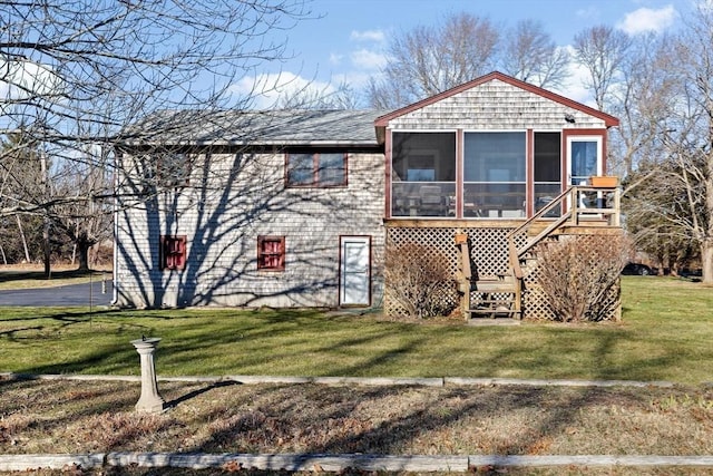 rear view of property with a lawn and a sunroom