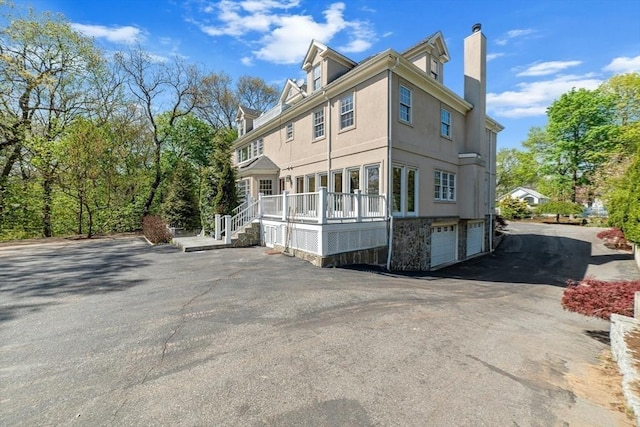 72 Charlemont St, Newton, MA 02461 - rear view of property with a chimney, stucco siding, and a garage