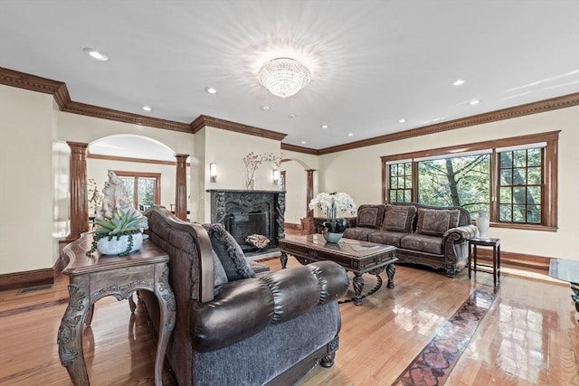 72 Charlemont St, Newton, MA 02461 - living room with decorative columns, light wood-style floors, a fireplace, arched walkways, and baseboards