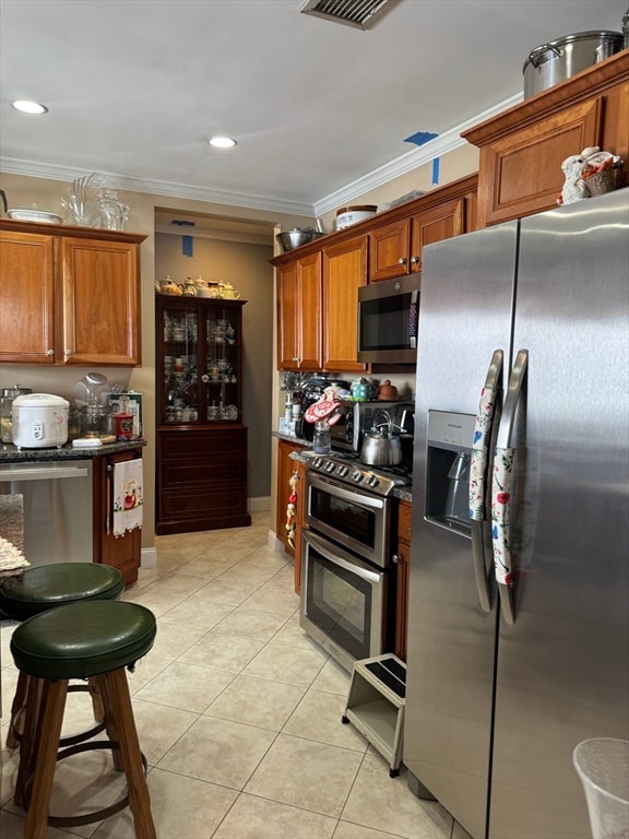 kitchen featuring crown molding, stainless steel appliances, and light tile patterned floors