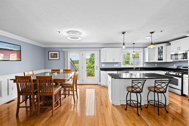 43 N Main St Unit B, Berkley, MA 02779 - kitchen with stainless steel appliances, a kitchen island, white cabinetry, crown molding, and light wood-type flooring