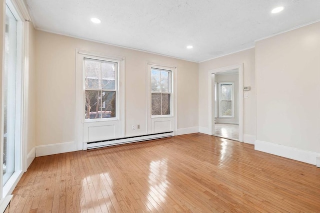 spare room with crown molding, a baseboard radiator, and light wood-type flooring