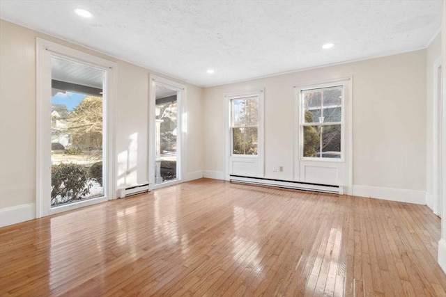 spare room with baseboard heating, a textured ceiling, and light wood-type flooring