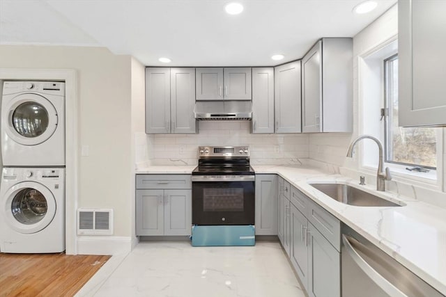 kitchen with stacked washer and dryer, sink, gray cabinetry, stainless steel appliances, and backsplash