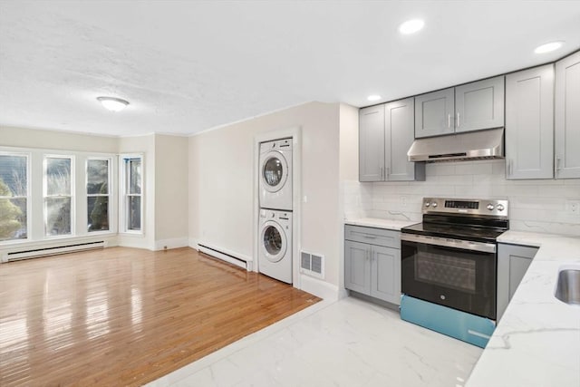 kitchen with electric stove, stacked washer and dryer, gray cabinetry, and baseboard heating