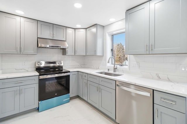 kitchen with sink, tasteful backsplash, gray cabinets, stainless steel appliances, and light stone countertops