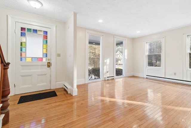 entryway featuring a textured ceiling, baseboard heating, and light hardwood / wood-style floors