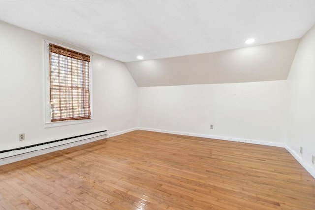 additional living space featuring baseboard heating, vaulted ceiling, and light wood-type flooring