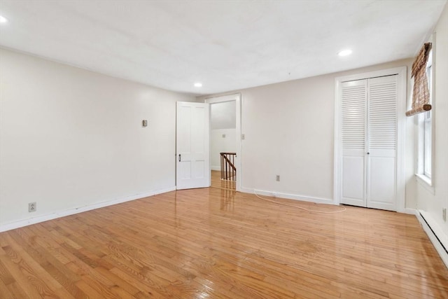 empty room with a baseboard radiator and light hardwood / wood-style flooring