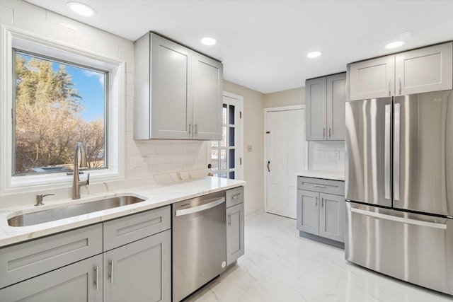 kitchen with sink, gray cabinets, stainless steel appliances, and light stone countertops