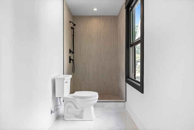 bathroom with toilet, a tile shower, and tile patterned floors