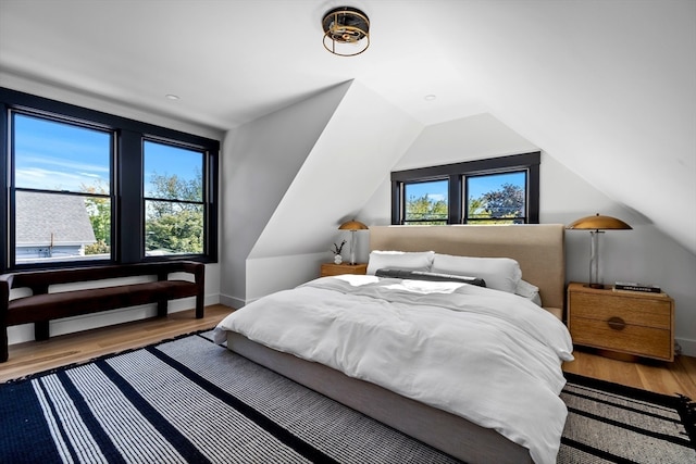 bedroom with wood-type flooring and vaulted ceiling