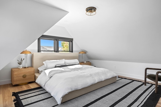 bedroom with vaulted ceiling and light wood-type flooring