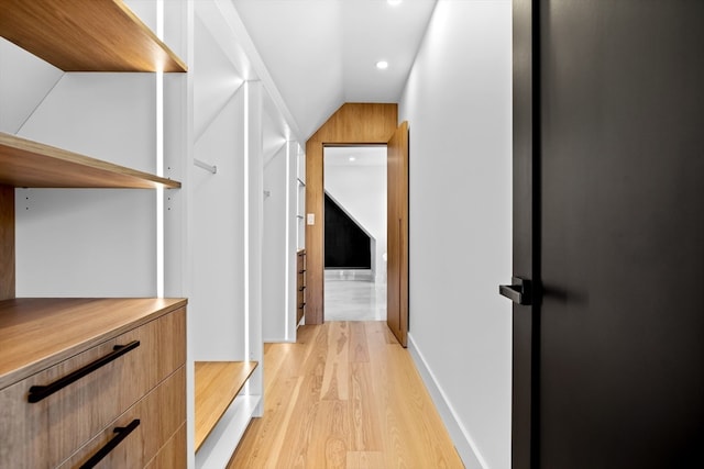 corridor featuring light hardwood / wood-style flooring and vaulted ceiling