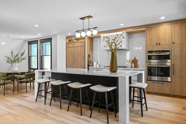 kitchen with a spacious island, stainless steel double oven, sink, and pendant lighting