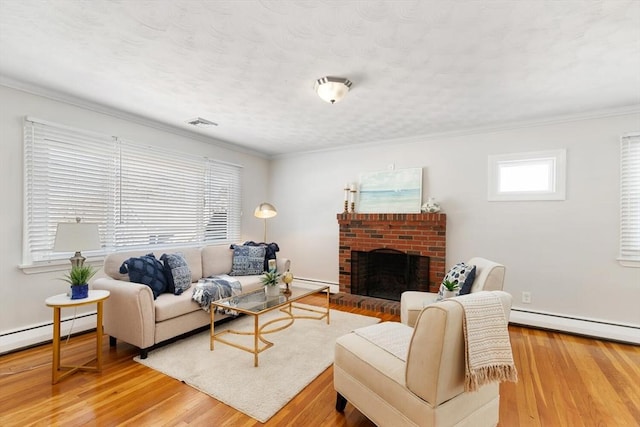 living room featuring wood-type flooring, a textured ceiling, baseboard heating, crown molding, and a brick fireplace