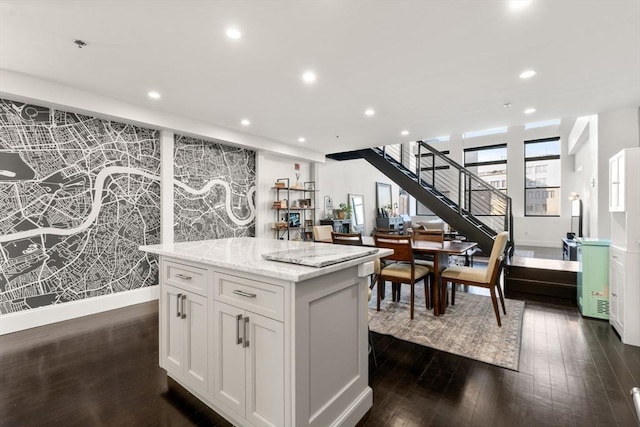 kitchen with white cabinets, a center island, dark hardwood / wood-style flooring, and light stone counters