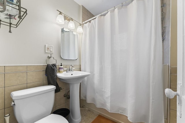 full bathroom with tile walls, shower / tub combo, sink, and toilet