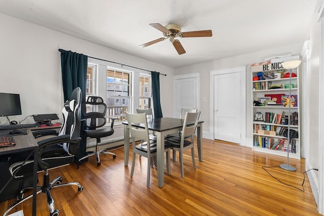 dining area featuring wood-type flooring, a baseboard heating unit, and ceiling fan