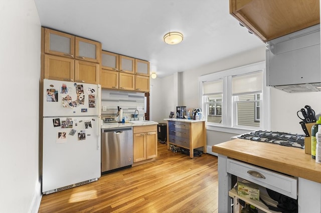 kitchen featuring dishwasher, sink, white refrigerator, gas stovetop, and light wood-type flooring