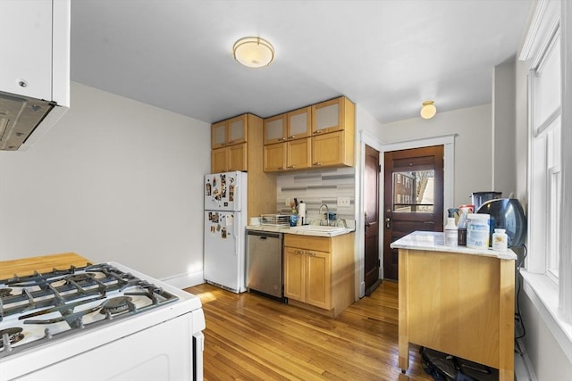 kitchen with backsplash, white appliances, sink, and light wood-type flooring