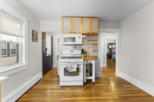 kitchen featuring light brown cabinetry, tasteful backsplash, hardwood / wood-style flooring, baseboard heating, and white appliances