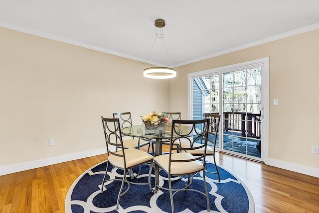 dining area featuring ornamental molding, baseboards, and wood finished floors