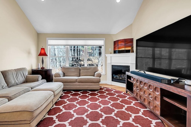 living room featuring vaulted ceiling, a glass covered fireplace, wood finished floors, and recessed lighting