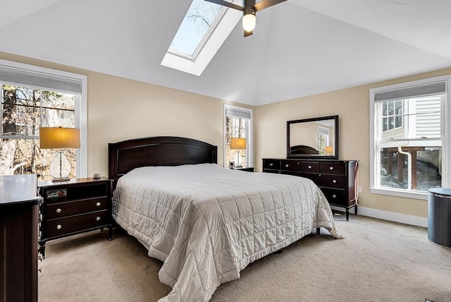 carpeted bedroom with lofted ceiling with skylight, multiple windows, baseboards, and a ceiling fan