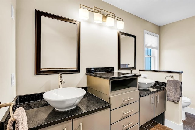 bathroom with two vanities, a sink, toilet, and baseboards