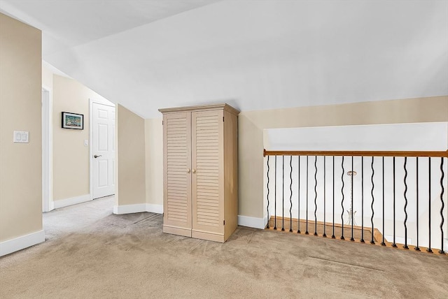 additional living space with light carpet, baseboards, and lofted ceiling