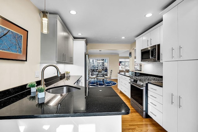 kitchen with a peninsula, light wood-style flooring, appliances with stainless steel finishes, and a sink